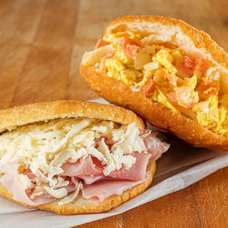 Two Chamo's Bagel & Grill sandwiches: one with ham and cheese, the other with scrambled eggs and vegetables.
